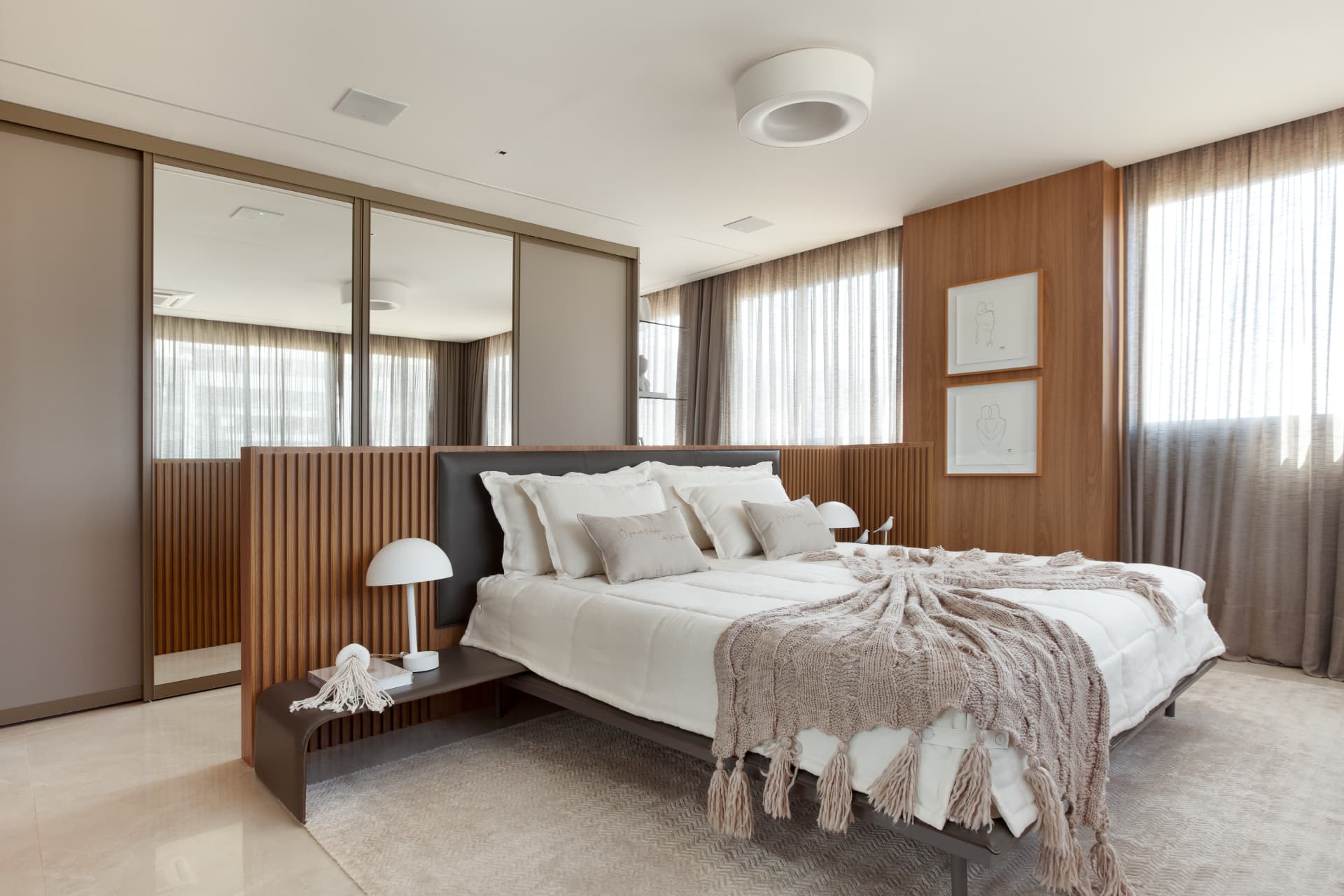 Suíte master do Apartamento L | K em Brasília com cama em linho claro, painel ripado de madeira, espelhos e luminária de difusão suave